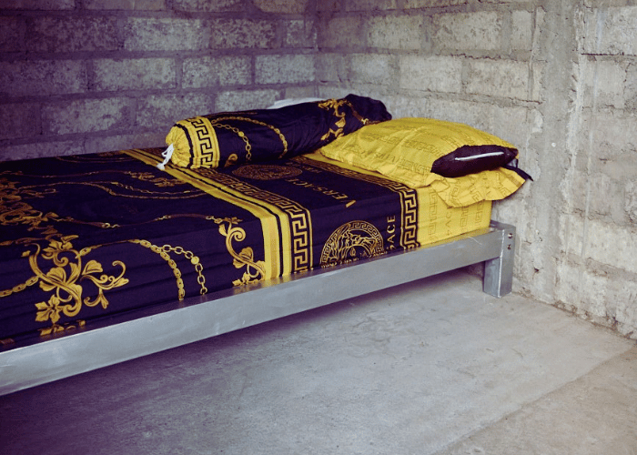 Metallbett mit Matratze in leerem Raum